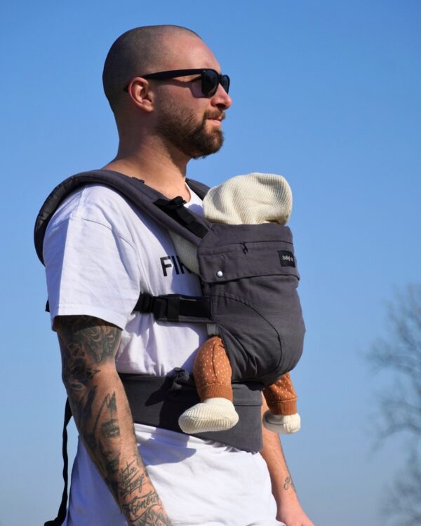Papa portant son bébé avec le porte-bébé Babylonia Flexia anthracite en coton biologique
