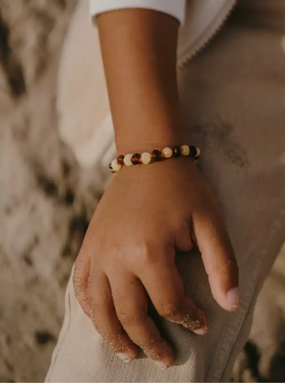 Bracelet d’ambre caramel et lait pour bébé porté au poignet