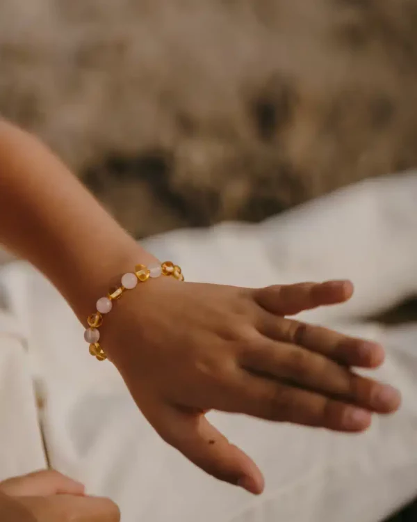Bracelet d’ambre pour enfant porté au poignet, modèle citron / quartz rose