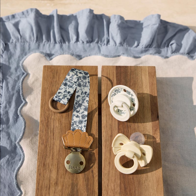 Pack Elodie “Garden” : attache-sucette et deux sucettes assorties posées sur planches en bois, lumière naturelle.