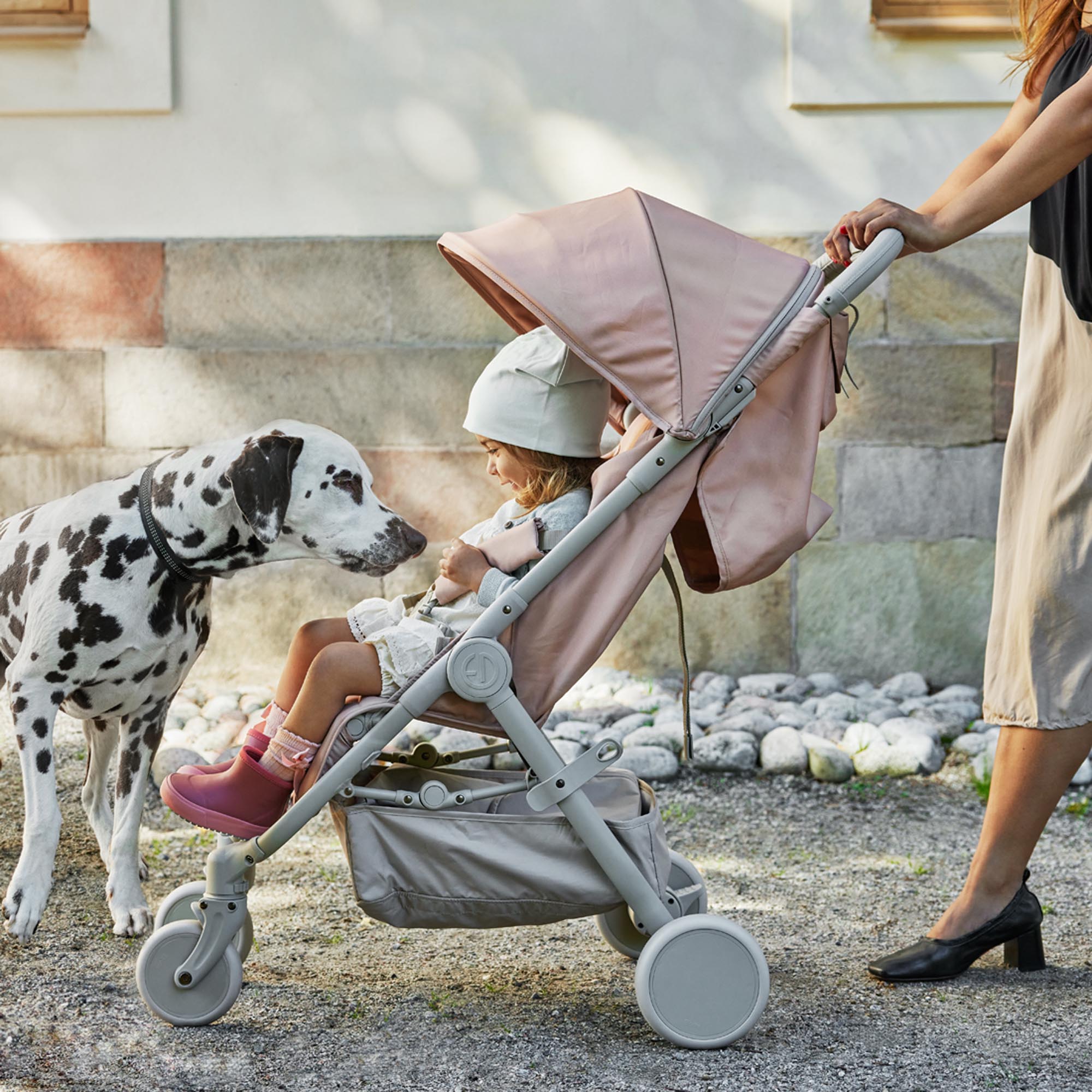Enfant dans la poussette Elodie MONDO Blushing Pink saluant un chien dalmatien pendant une promenade