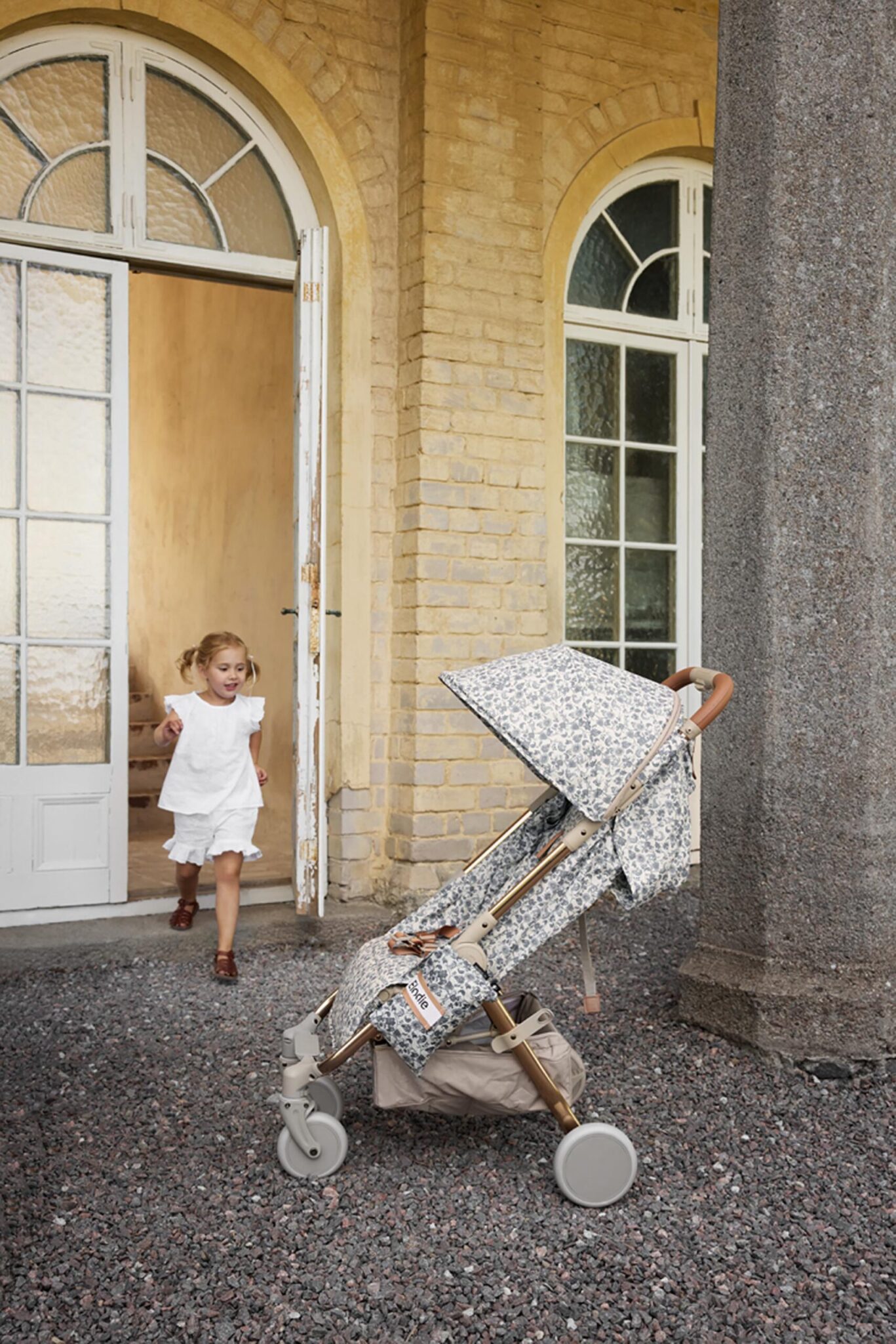 Poussette compacte Elodie MONDO Garden Leo stationnée devant une maison, prête pour une promenade