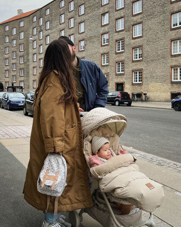 Parents en ville avec bébé dans une poussette, chancelière Elodie Pure Khaki visible