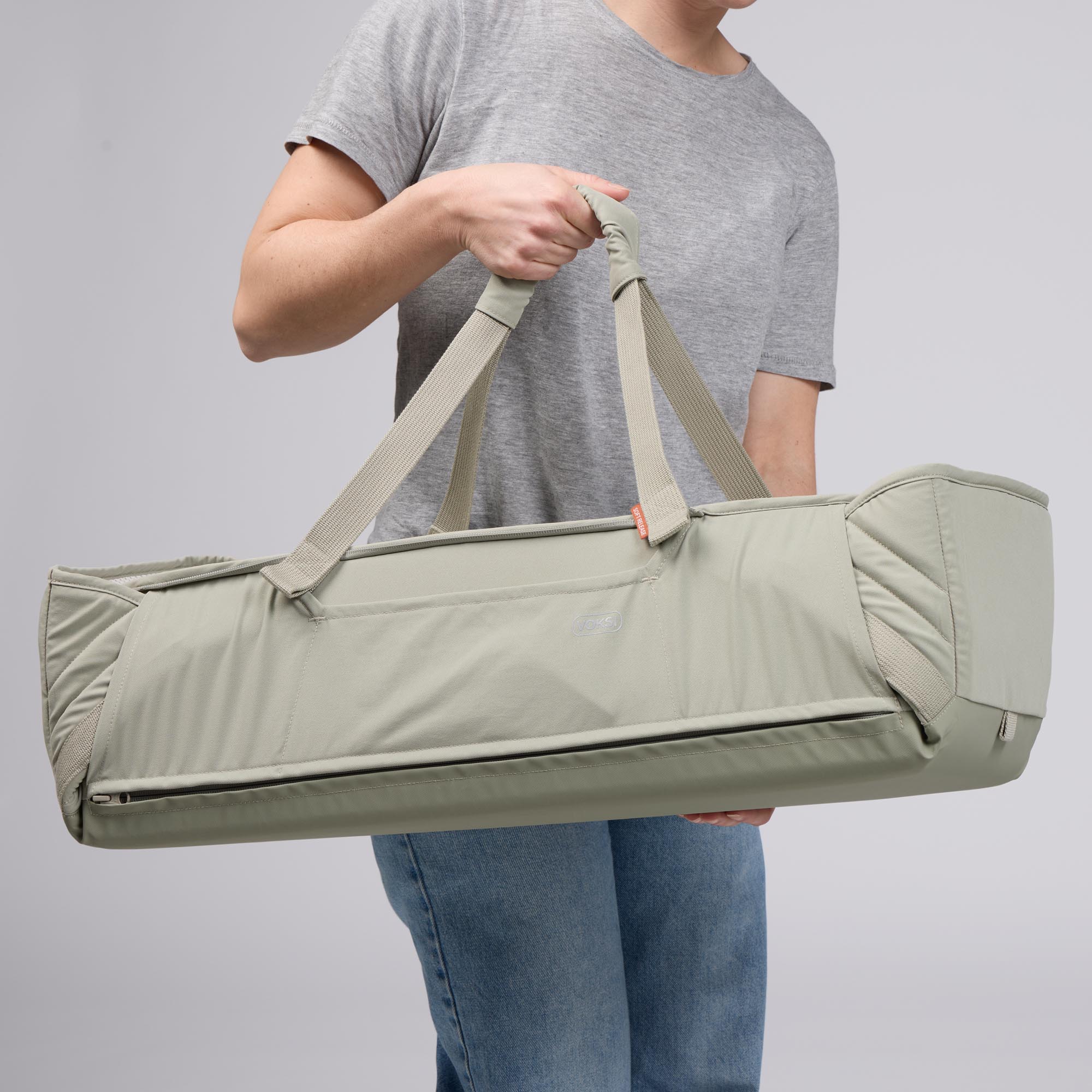 Voksi Carry Me vert sauge portée à la main, couffin de transport bébé avec anses et fermeture zippée.