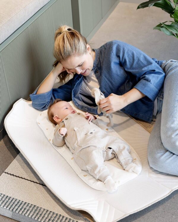 Parent joue avec bébé sur un matelas Voksi Carry Me, surface d’appoint confortable pour l’éveil à la maison.