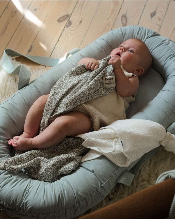 Bébé allongé dans le couffin portable Elodie Baby Nest Mineral Green, ambiance douce et cocooning