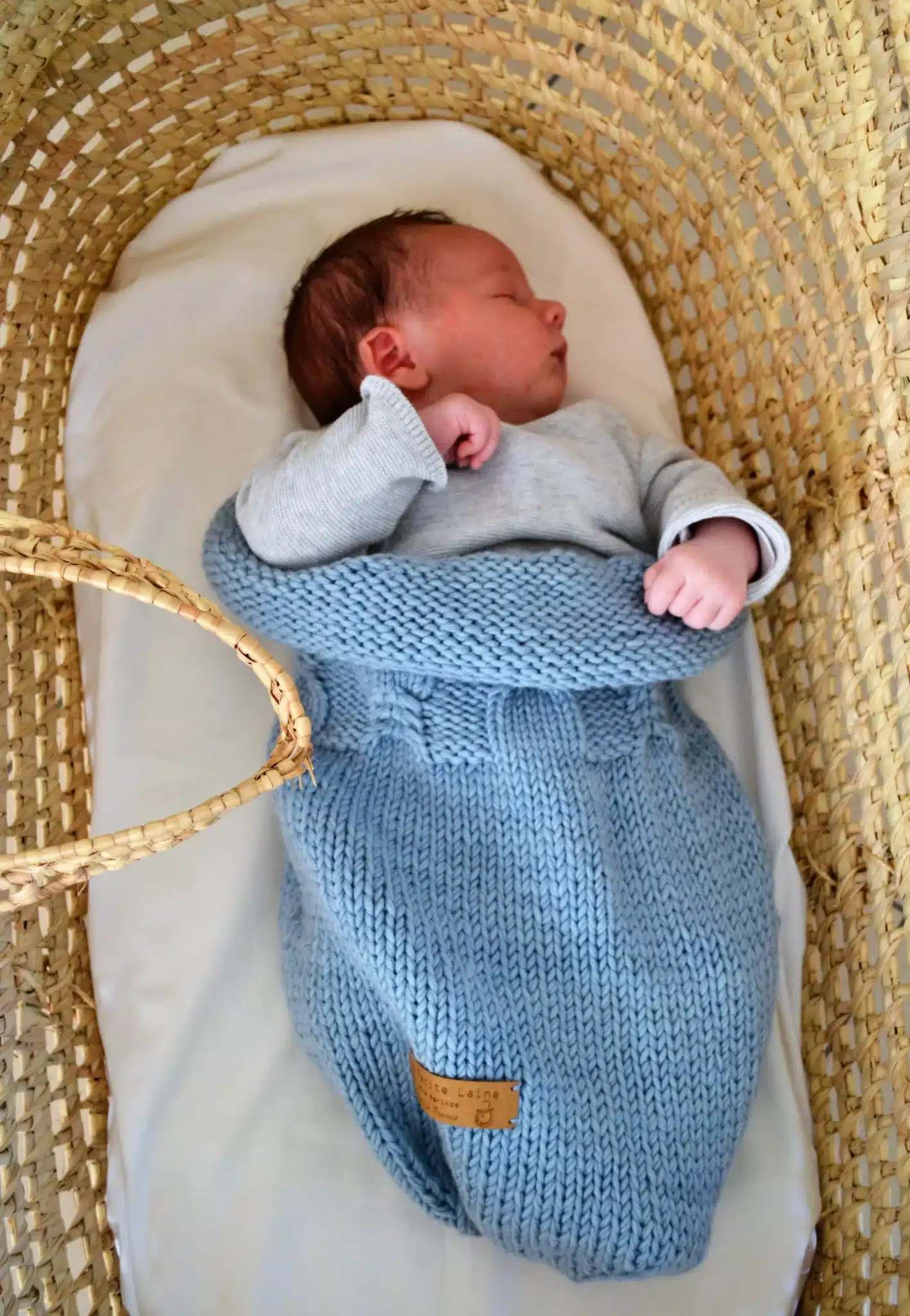 Nouveau-né endormi dans un cocon de naissance en laine mérinos bleu layette Ma Petite Laine