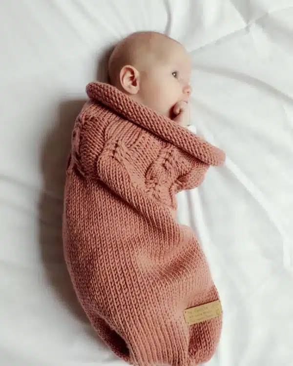 Bébé allongé dans un cocon de naissance en laine mérinos terracotta Ma Petite Laine
