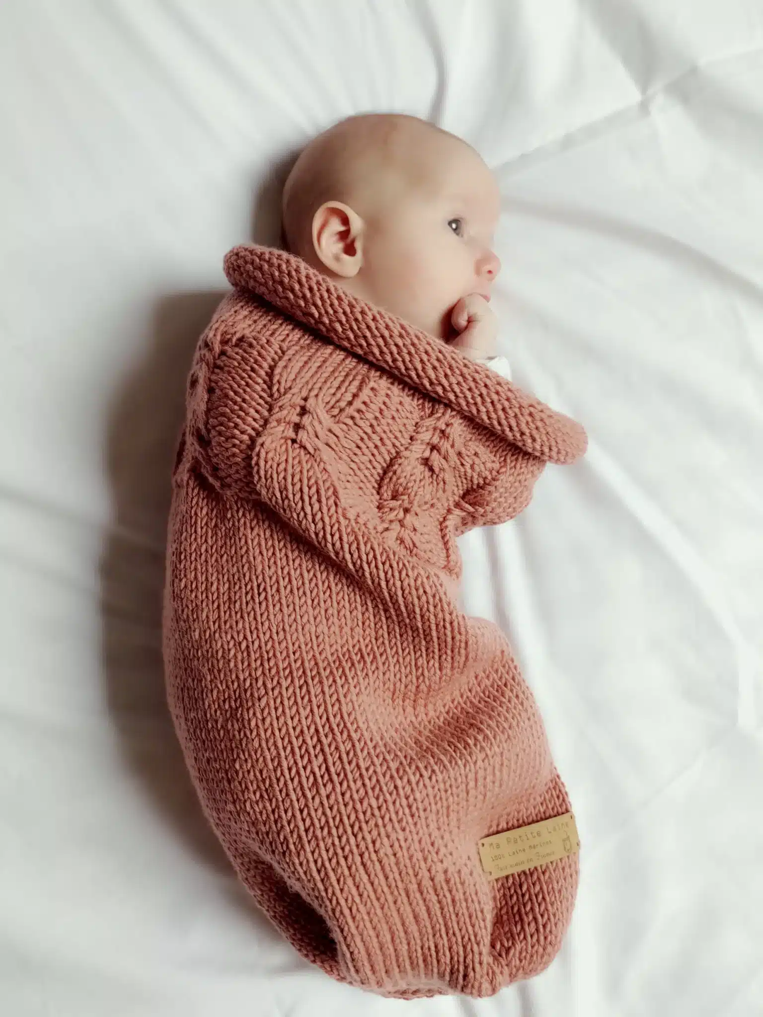 Bébé allongé dans un cocon de naissance en laine mérinos terracotta Ma Petite Laine