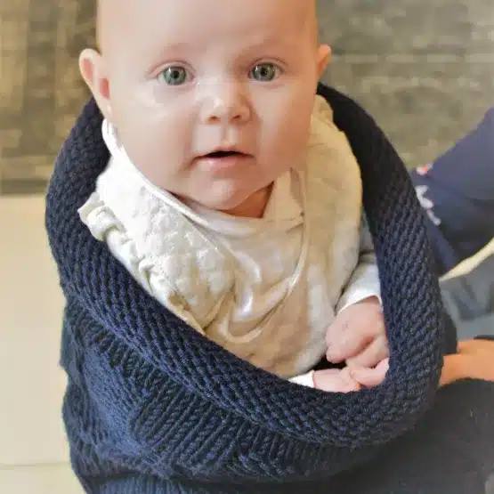 Bébé éveillé dans un cocon de naissance en laine mérinos marine, emmaillotage confortable
