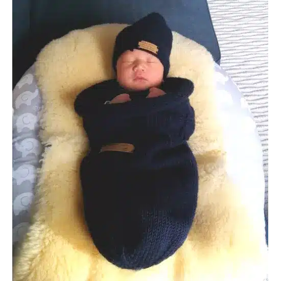 Nouveau-né endormi dans un cocon de naissance en laine mérinos marine, fabriqué en France
