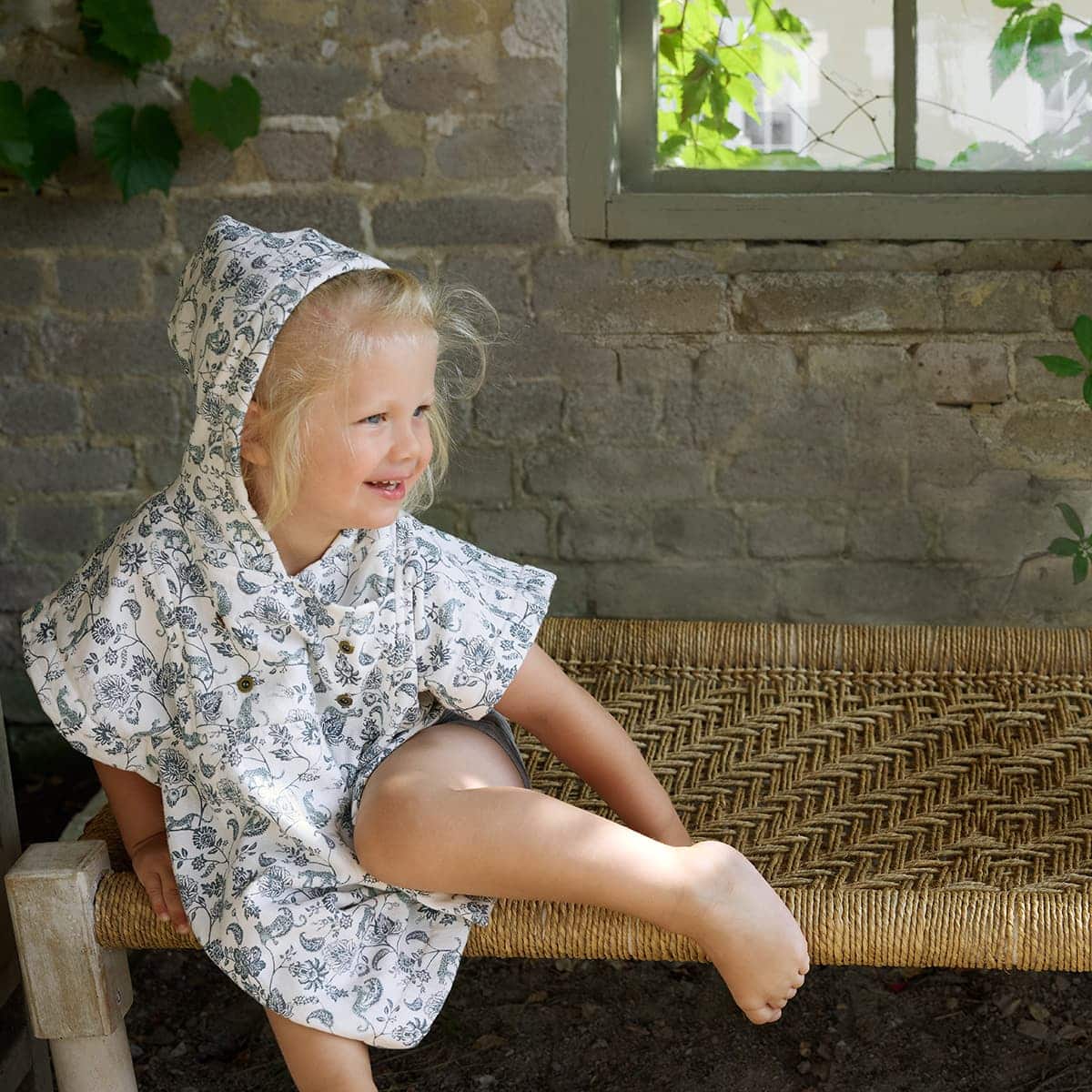 Enfant portant le poncho de bain Elodie Garden Leo Toile dans un décor naturel