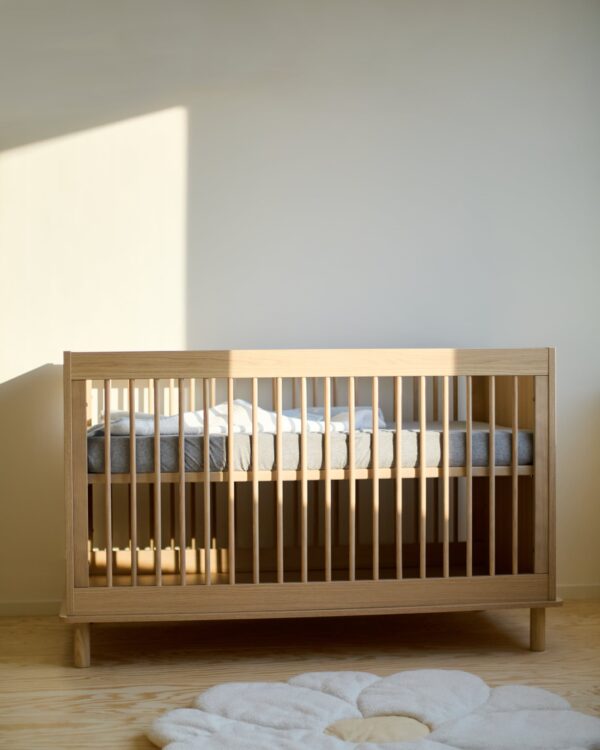 Vue de face du lit bébé évolutif Childhome Nordica Natural dans une chambre bébé