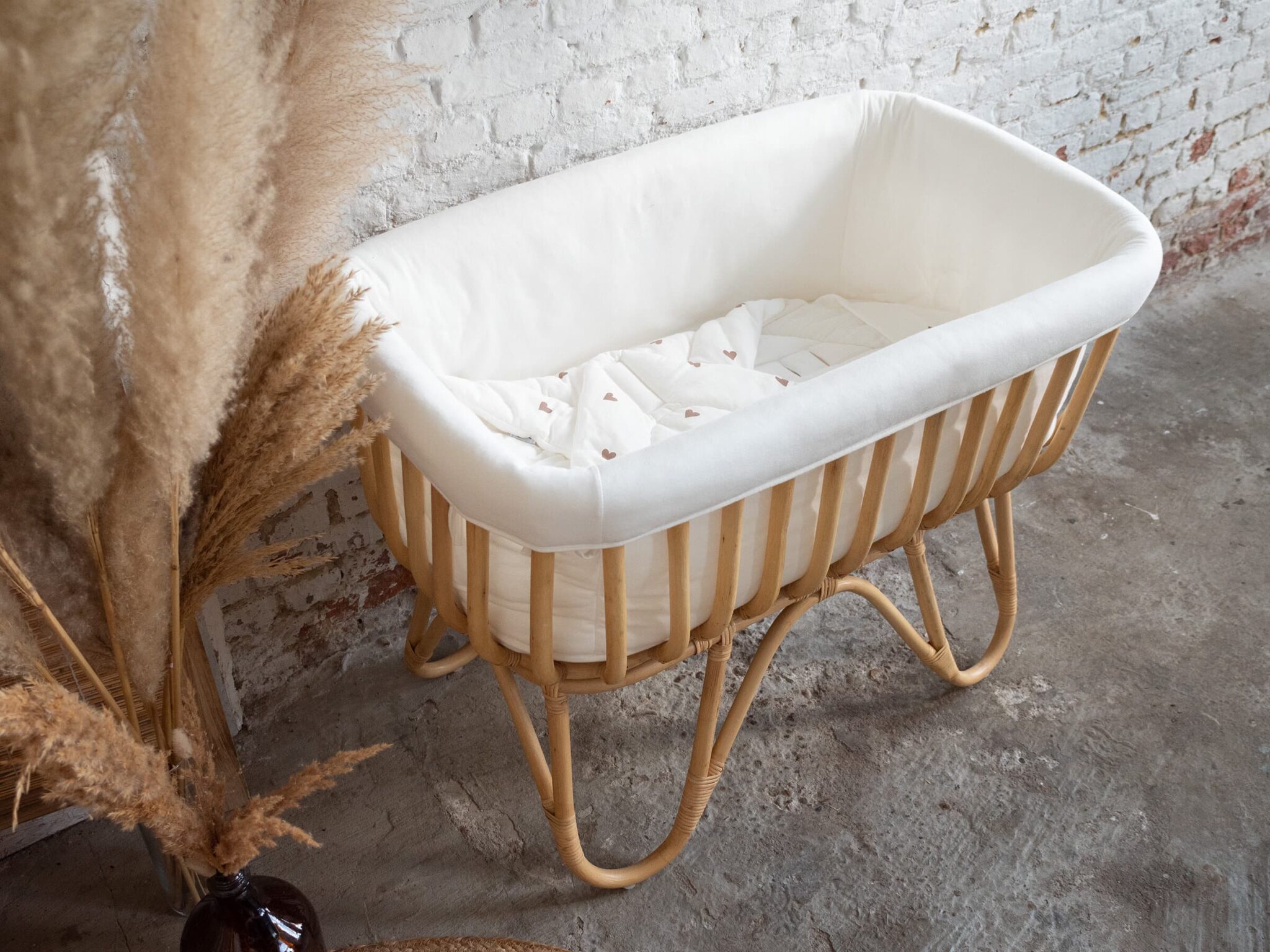 Berceau en rotin Childhome avec linge de lit dans une chambre bébé au style bohème