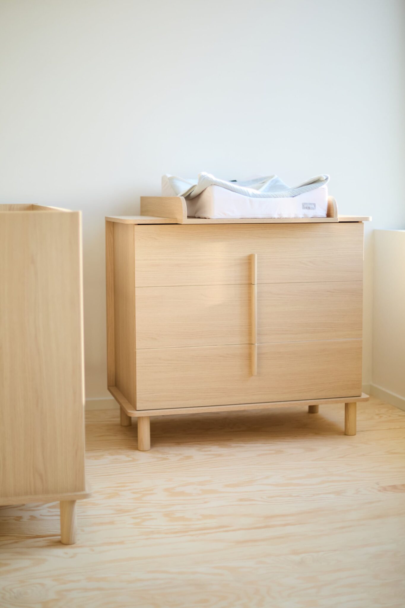 Commode bébé Childhome Nordica Natural avec plan à langer dans une chambre bébé lumineuse