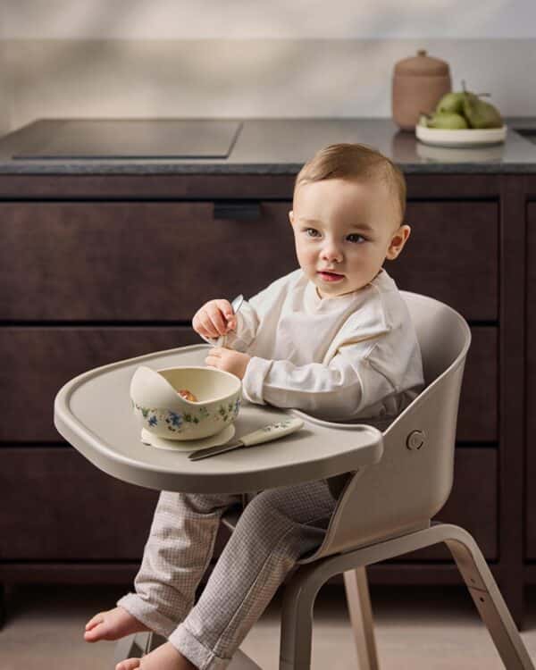 Bébé installé dans la chaise haute évolutive Elodie GRACE Tender Taupe pendant le repas